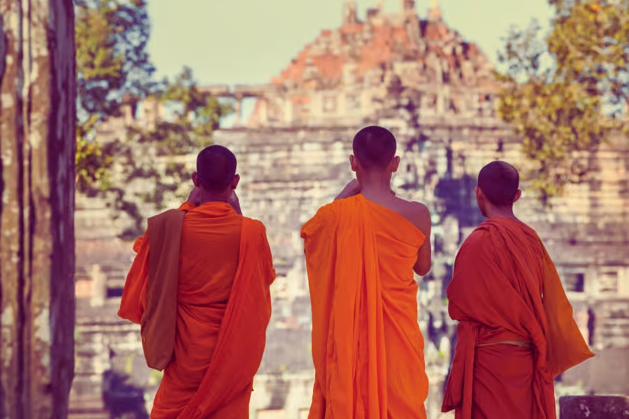 Three Buddhist monks in orange robes visiting Angkor temple, Cambodia – Auasia Travel